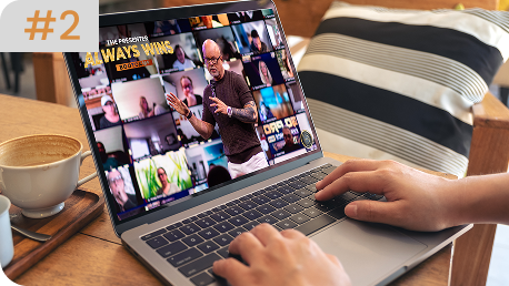 Close-up of hands typing on a laptop displaying a Zoom-style virtual meeting titled "The Presenter Always Wins Bootcamp" featuring Eric Worre.